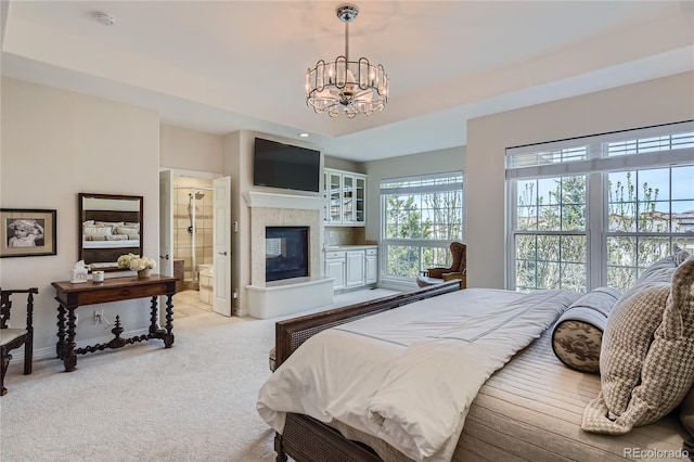 bedroom with light colored carpet, ensuite bathroom, an inviting chandelier, and a multi sided fireplace