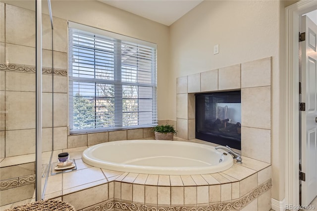 bathroom featuring tiled bath and a tiled fireplace