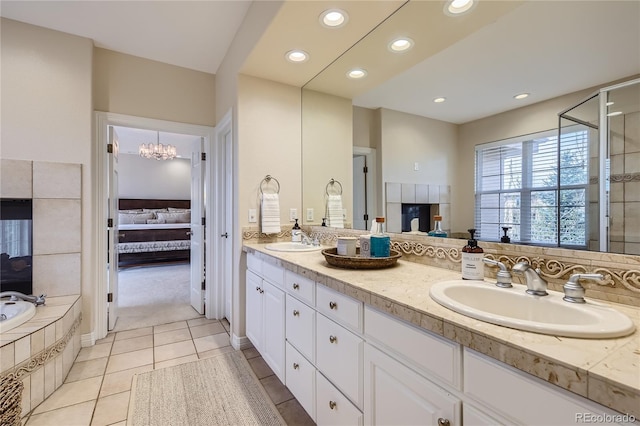 bathroom with a relaxing tiled tub, double vanity, a chandelier, and tile patterned floors