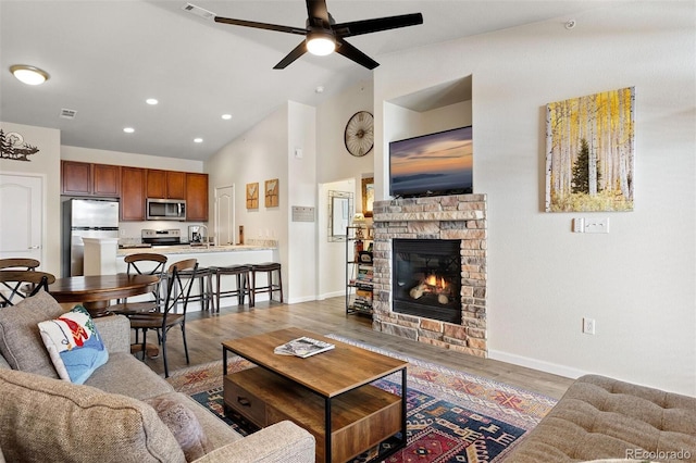 living room with a stone fireplace, vaulted ceiling, ceiling fan, dark hardwood / wood-style flooring, and sink