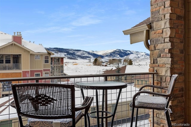 snow covered back of property featuring a mountain view