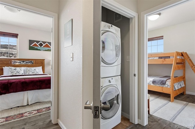 washroom featuring dark hardwood / wood-style flooring and stacked washer / drying machine