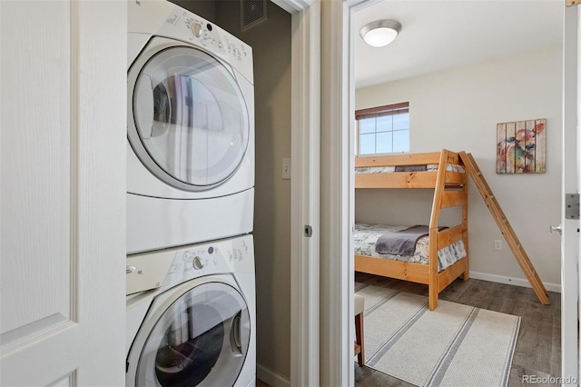 laundry room with stacked washer and clothes dryer and dark hardwood / wood-style flooring