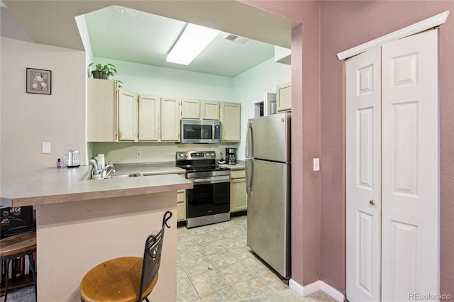 4545 Wheaton Dr Unit B210, Fort Collins, CO 80525 - kitchen featuring appliances with stainless steel finishes, a peninsula, light countertops, and a kitchen bar