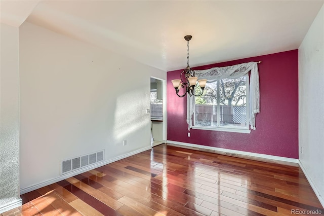 unfurnished dining area with wood-type flooring and a notable chandelier