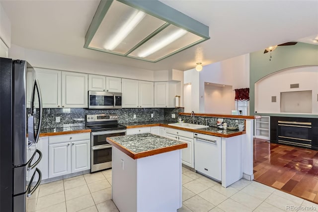 kitchen with sink, stainless steel appliances, a center island, and white cabinets