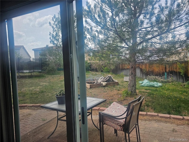 3811 Lisbon Ct, Denver, CO 80249 - view of patio featuring a trampoline, a fenced backyard, and outdoor dining area