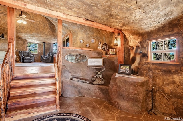 interior space with a wood stove and ceiling fan