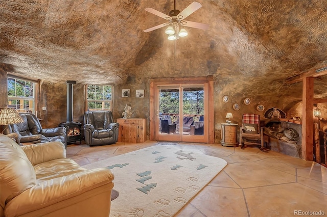 interior space with a wood stove, vaulted ceiling, ceiling fan, and plenty of natural light