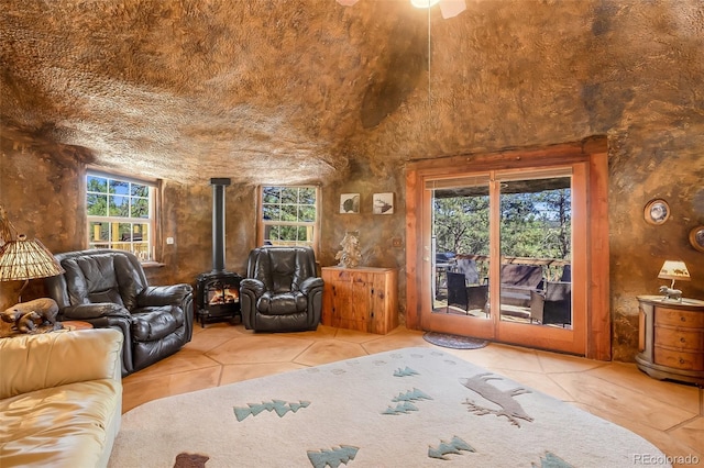 living room featuring a wood stove, vaulted ceiling, and light tile patterned floors