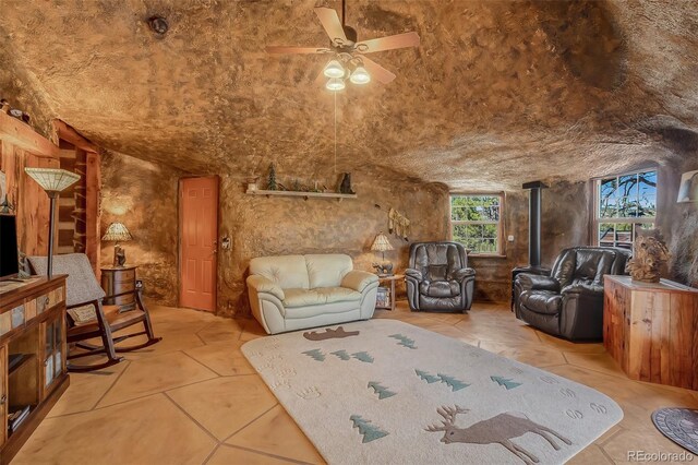 living room with ceiling fan, lofted ceiling, and a wood stove