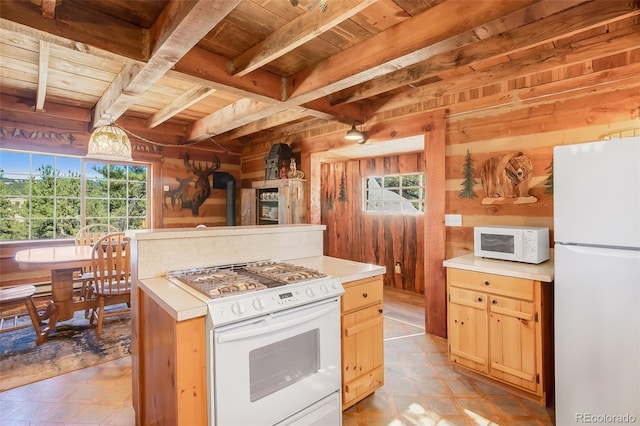 kitchen featuring beamed ceiling, wood walls, a wood stove, white appliances, and wooden ceiling