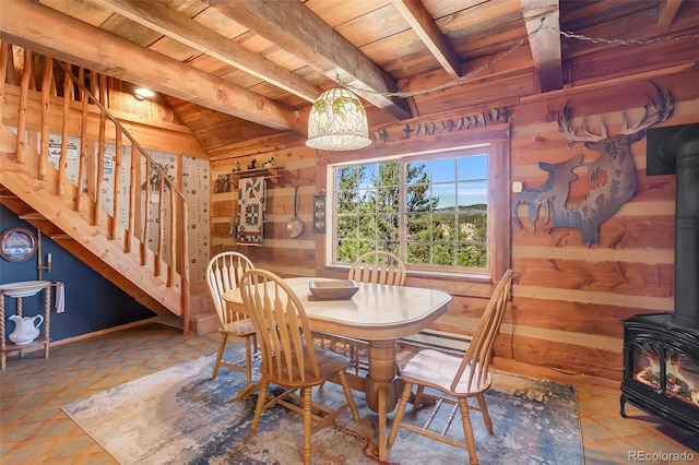 dining space with wood walls, wood ceiling, lofted ceiling with beams, and a wood stove