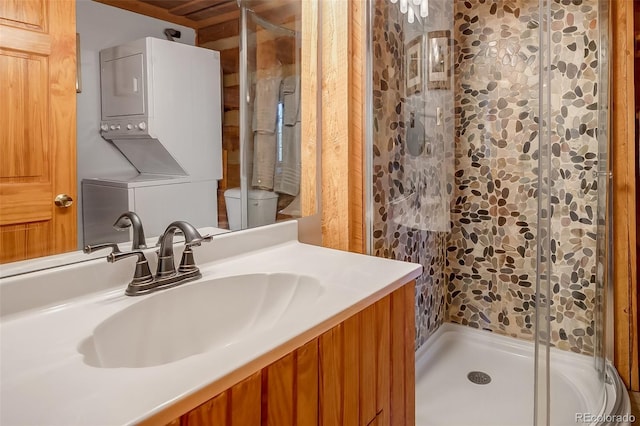 bathroom featuring stacked washer / drying machine, vanity, toilet, and walk in shower