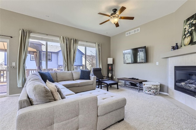 carpeted living room featuring ceiling fan and a fireplace