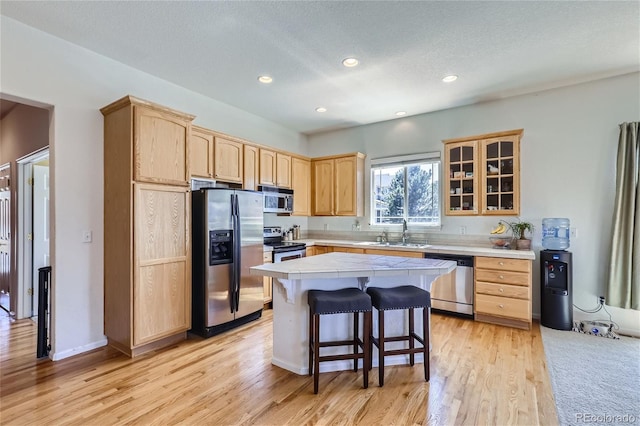 kitchen featuring stainless steel appliances, sink, light brown cabinets, and light hardwood / wood-style floors