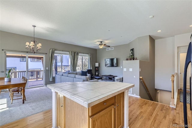 kitchen featuring tile counters, a center island, light hardwood / wood-style floors, and hanging light fixtures