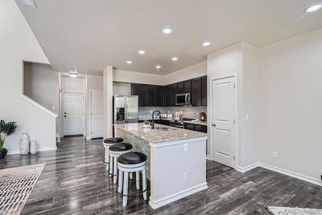 3611 S Perth Cir Unit 103, Aurora, CO 80013 - kitchen featuring stainless steel appliances, dark wood-style flooring, light stone countertops, a kitchen island with sink, and recessed lighting