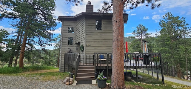 27901 Pine Dr, Evergreen, CO 80439 - view of side of home featuring a wooden deck, a chimney, and stairs