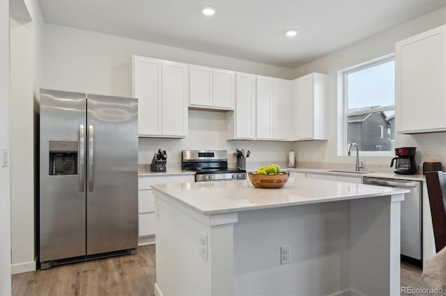 kitchen with white cabinets, a center island, stainless steel appliances, and sink