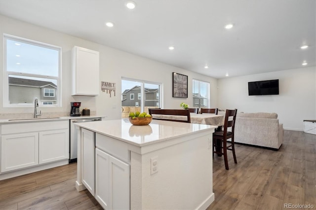 kitchen featuring white cabinetry, a center island, dishwasher, sink, and light hardwood / wood-style flooring