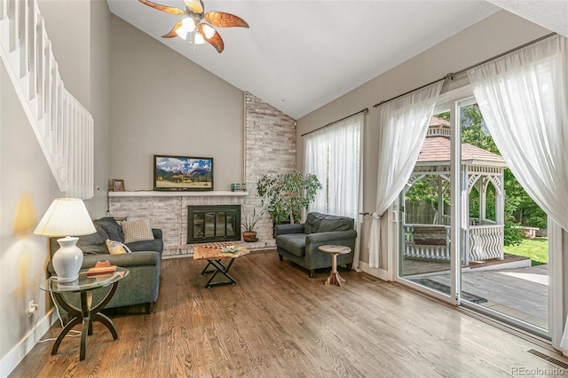 living room featuring a fireplace, hardwood / wood-style floors, high vaulted ceiling, and ceiling fan