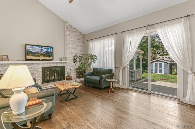 sitting room with a brick fireplace, high vaulted ceiling, and hardwood / wood-style flooring