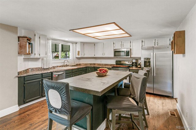 kitchen featuring dark hardwood / wood-style flooring, a skylight, a breakfast bar, stainless steel appliances, and sink