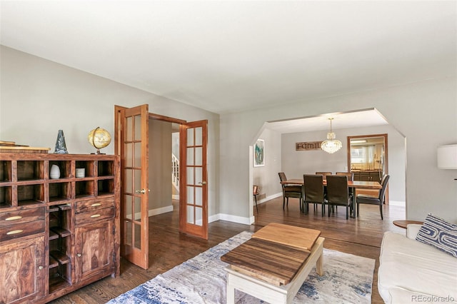 living room with an inviting chandelier, dark wood-type flooring, and french doors