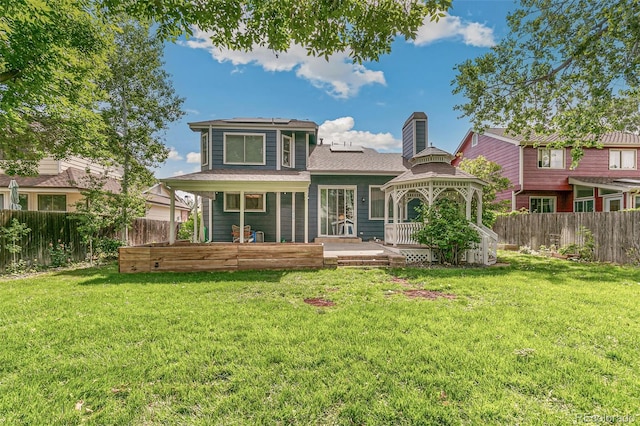 rear view of property featuring a gazebo, a wooden deck, and a lawn