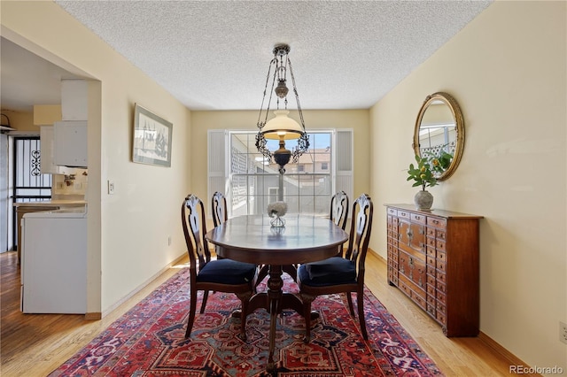 2608 E Fremont Pl, Centennial, CO 80122 - dining space with light wood-style floors, washer / dryer, a textured ceiling, and baseboards