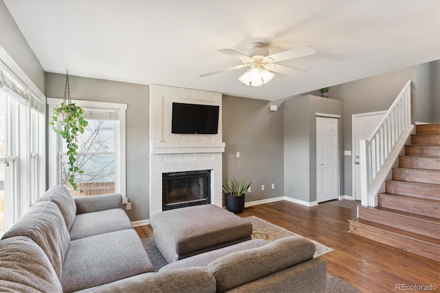 living room with dark hardwood / wood-style floors, a brick fireplace, and ceiling fan