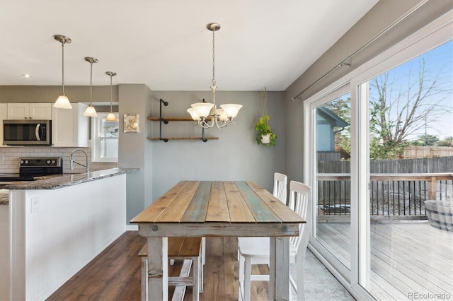 dining space featuring sink, dark hardwood / wood-style floors, and a notable chandelier