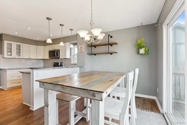 dining area with light wood-type flooring and an inviting chandelier