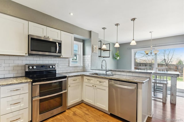 kitchen with plenty of natural light, kitchen peninsula, sink, and appliances with stainless steel finishes