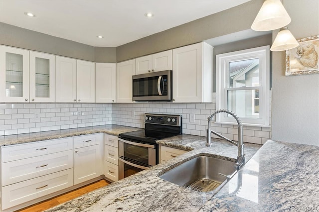 kitchen with backsplash, sink, decorative light fixtures, white cabinetry, and stainless steel appliances