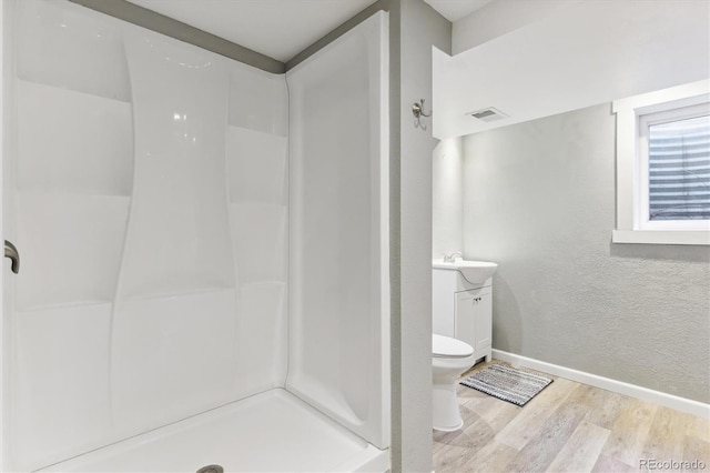 bathroom featuring hardwood / wood-style flooring, toilet, a shower, and vanity