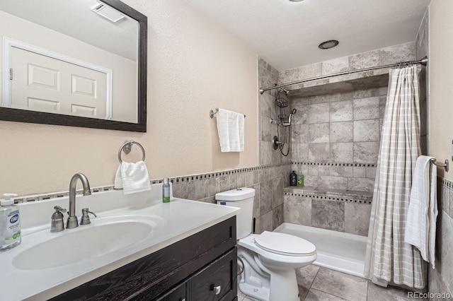 11759 E Asbury Ave, Aurora, CO 80014 - bathroom featuring tile walls, tile patterned floors, vanity, a tile shower, and a wainscoted wall