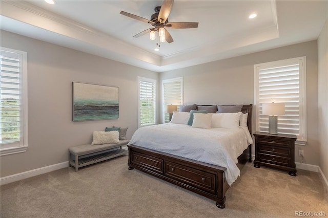 bedroom featuring crown molding, light colored carpet, a tray ceiling, recessed lighting, and baseboards