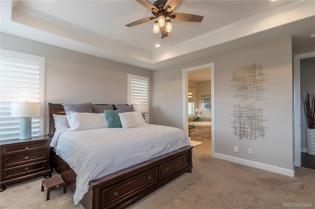 bedroom with light colored carpet, ornamental molding, a raised ceiling, baseboards, and ensuite bathroom
