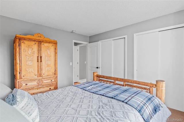 bedroom with carpet flooring, a textured ceiling, and multiple closets