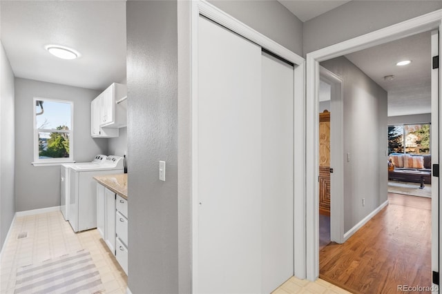 laundry room with washing machine and dryer, baseboards, light floors, and cabinet space