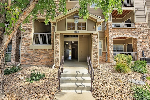 view of exterior entry featuring a balcony and central AC