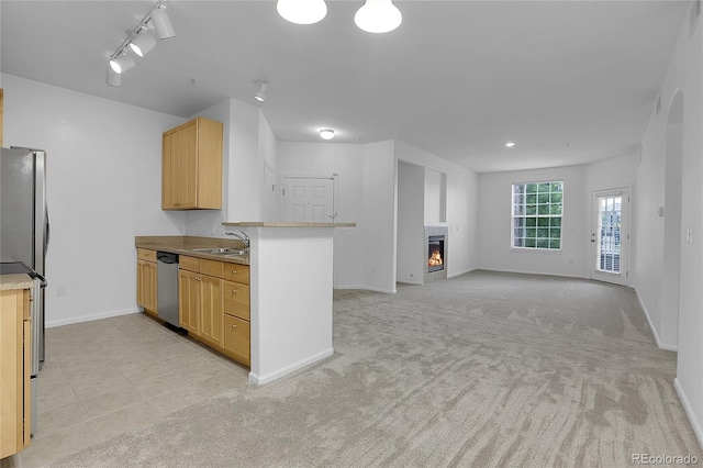 kitchen featuring kitchen peninsula, stainless steel appliances, light brown cabinetry, sink, and light carpet