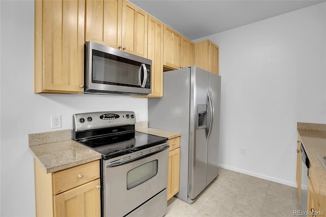 kitchen featuring light stone countertops, light brown cabinetry, light tile patterned floors, and stainless steel appliances