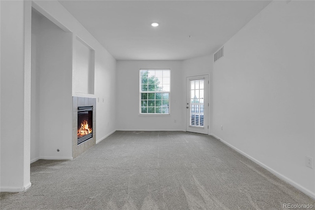 unfurnished living room with light colored carpet and a tiled fireplace