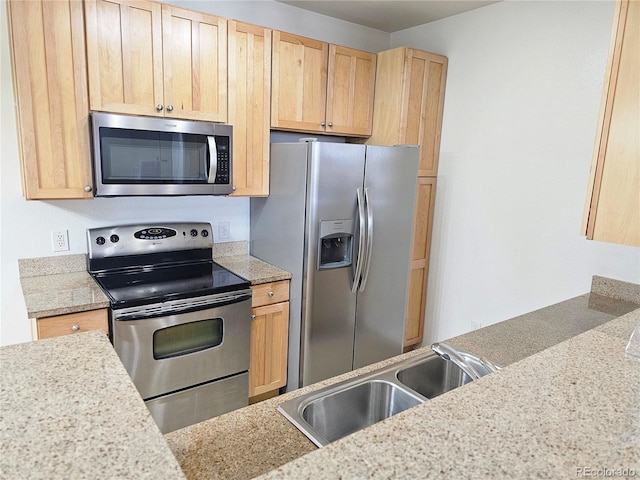 kitchen featuring light brown cabinetry, appliances with stainless steel finishes, light stone countertops, and sink