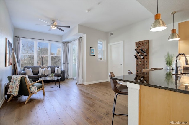 living room with a ceiling fan, baseboards, visible vents, and wood finished floors