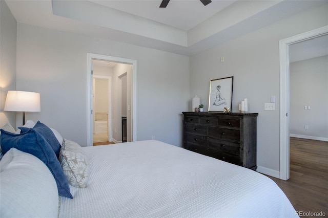 bedroom featuring a raised ceiling, ceiling fan, hardwood / wood-style floors, and ensuite bath