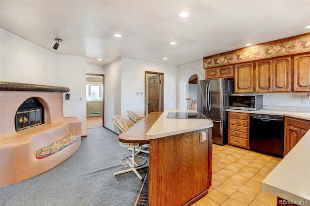 kitchen featuring a breakfast bar, a center island, light tile patterned floors, baseboard heating, and black appliances